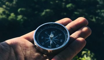 A hand holding a compass