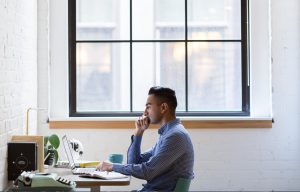 a man seating at his desk and working with a laptop