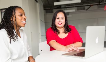 Two smiling women looking at a laptop