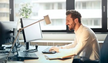 Man sitting at desk with computer in front of a window